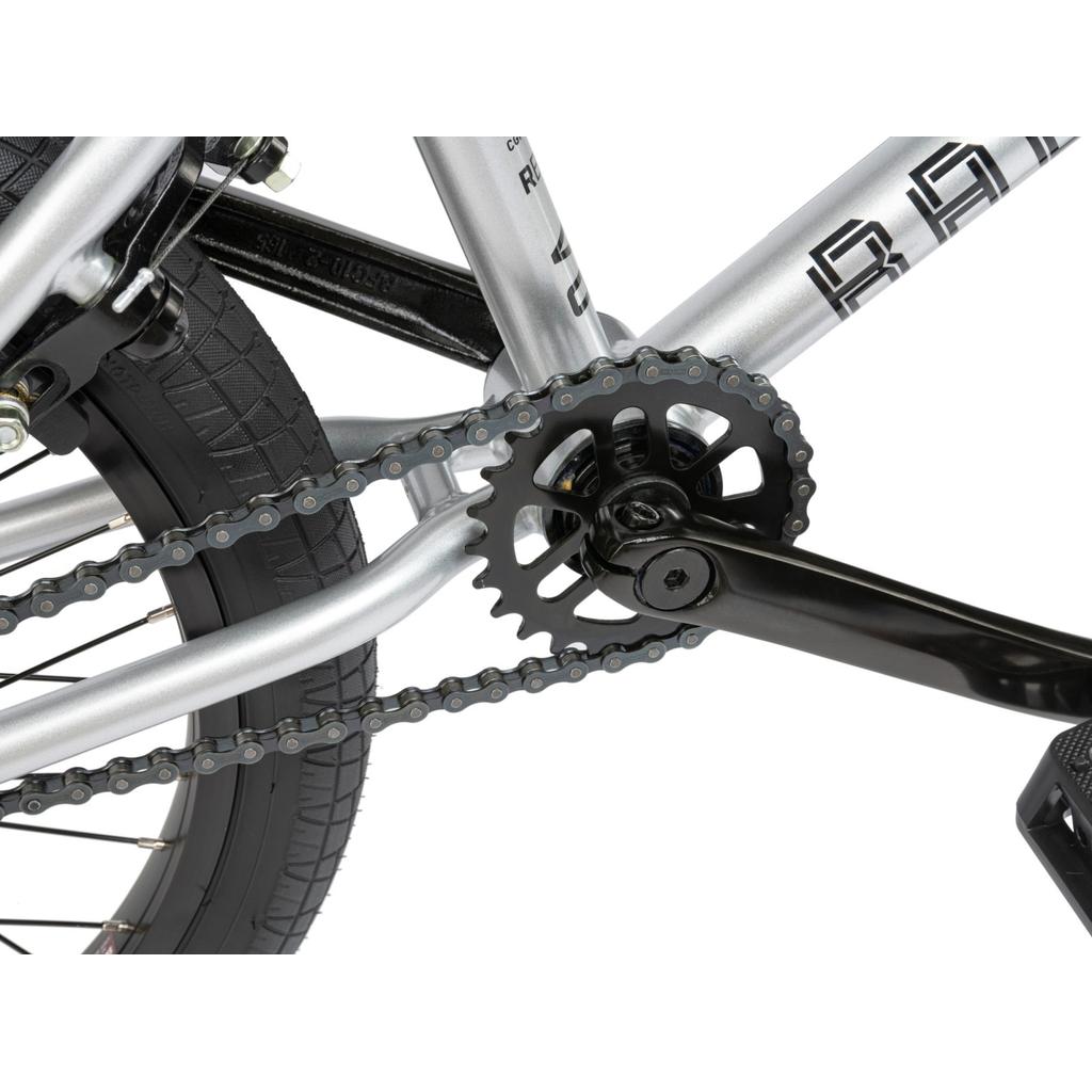 Close-up view of a BMX bike crankset, chainring, and chain—showing part of the rear wheel and frame, like those on the Radio Revo Pro 20 Inch Bike.