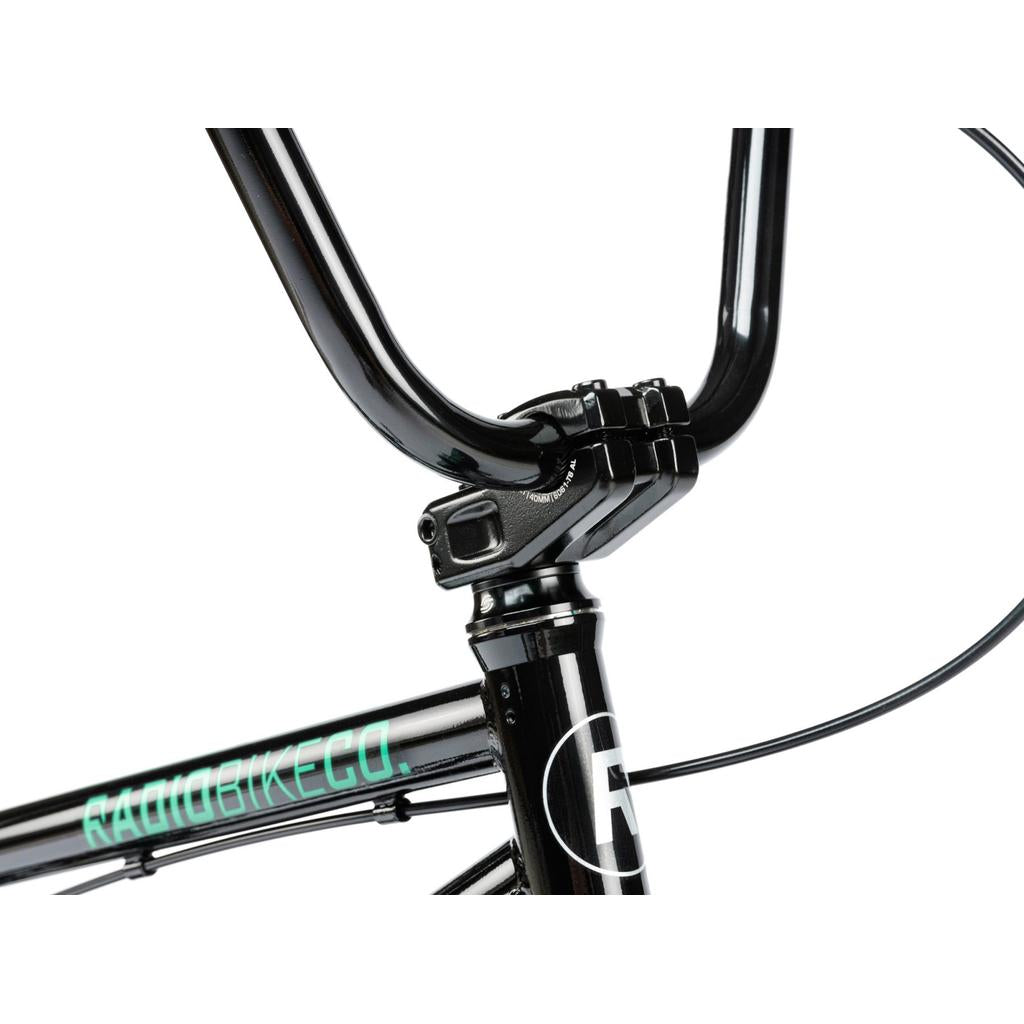 Close-up of black BMX handlebars and stem with visible cables; "RADIOBIKECO." logo partially shown on the frame, featuring Salt Tracer Tyres on the Radio Saiko 18 Inch Bike—an ideal kids BMX bike.
