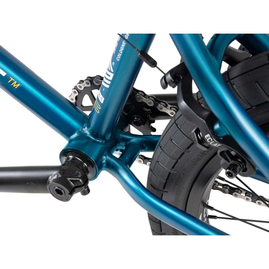 Close-up of the Wethepeople Arcade 20 Inch Bike in turquoise, featuring its mid-tier BMX frame, bottom bracket, chain, crank arm, part of the rear wheel, and Salt Valon Rims.