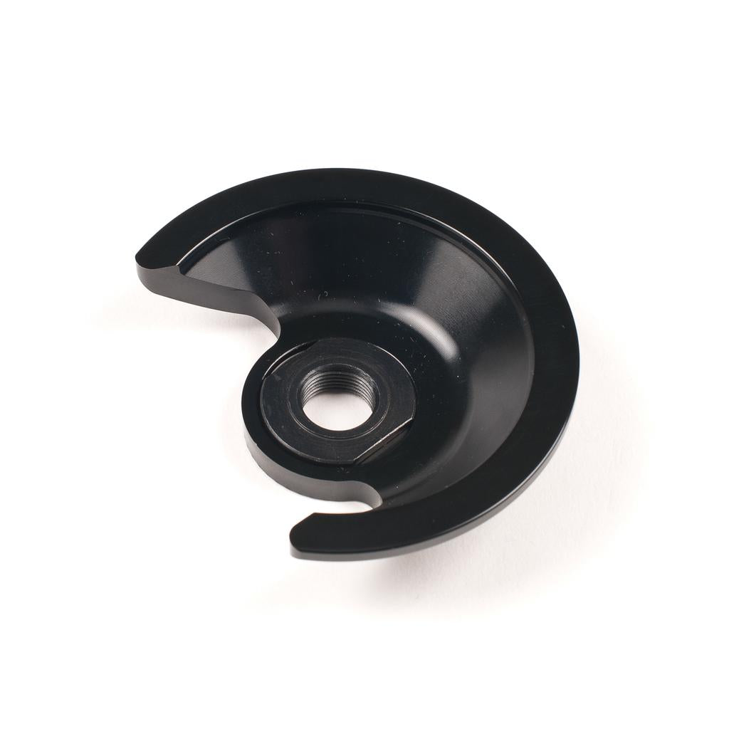 A Saltplus Trapez F/C Hubguard Alloy, black and semi-circular with a central threaded hole, is shown on a white background.