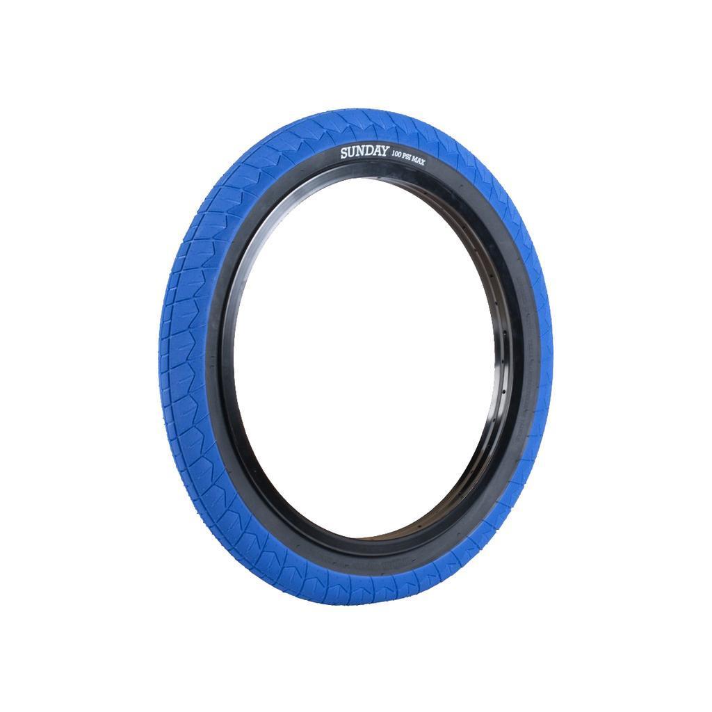 The Sunday Current V2 Tyre (Each) is a blue BMX tire with black sidewalls, "SUNDAY" and "100 PSI MAX" printed on the side, offering affordable performance and a grippy tread for better control.