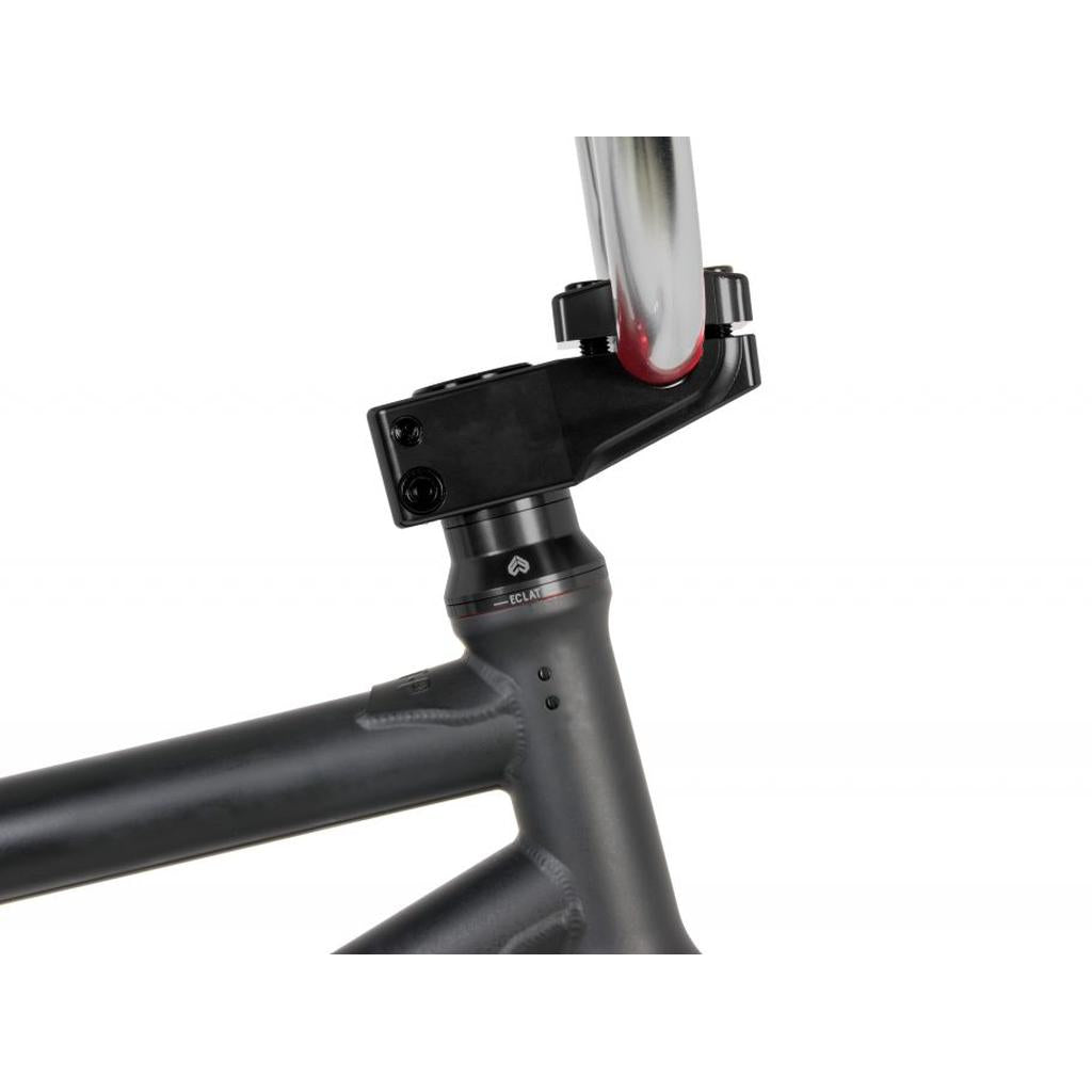 Close-up of a bicycle's matte black frame showcasing the Eclat Dune Stem, a 6061-T6 alloy top loader at the headset and handlebar connection, highlighting premium BMX components.