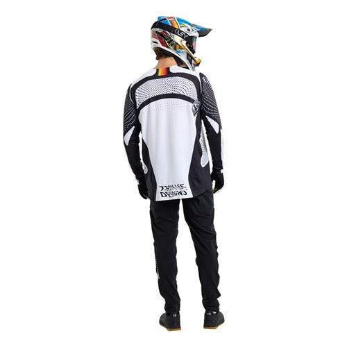 A person wearing the TLD 26.1 Sprint Ultra Pant / Mono Black motocross pants and a black and white outfit stands facing away from the camera against a white background.