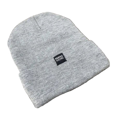 The Profile Woven Label Beanie, a light gray knit beanie featuring a black "Profile Racing" woven label, is displayed on a wooden surface, highlighting its quality and union-made craftsmanship.