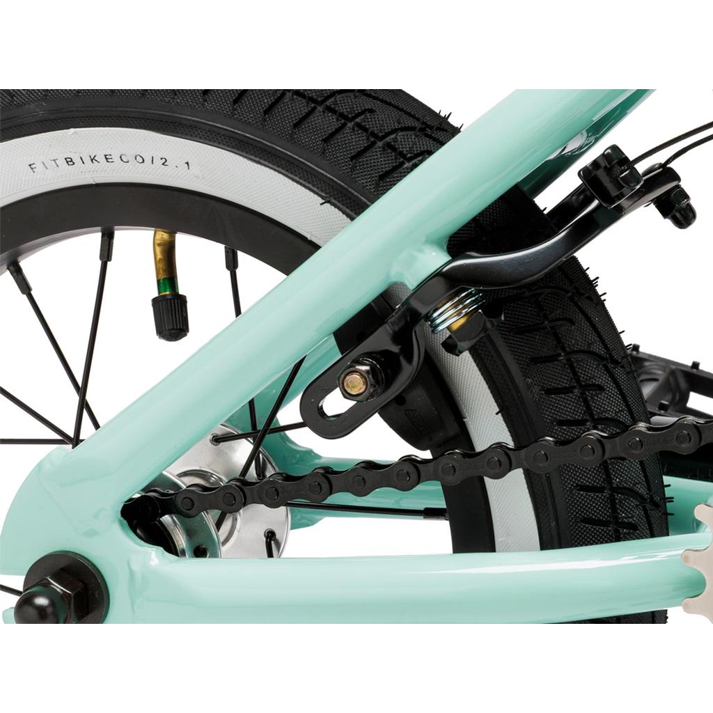 Close-up of the Fit Misfit 12 Inch Bike’s rear wheel, highlighting the tire, chain, brakes, and a section of its light blue kids’ pedal frame.