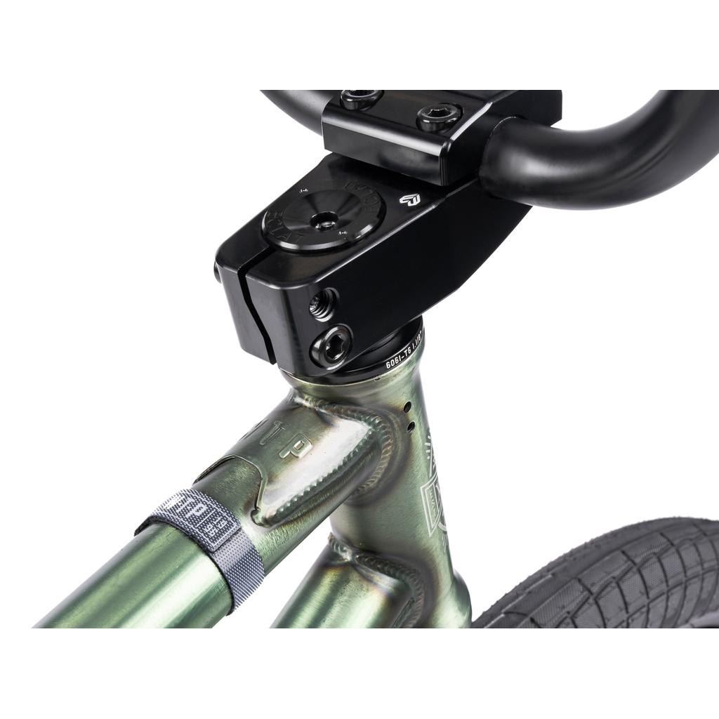 Close-up of the Wethepeople Revolver 20 Inch Bike’s handlebar stem, headset, and front wheel, highlighting welded joints and sleek metallic green frame with a textured black tire—showcasing high-quality aftermarket details.