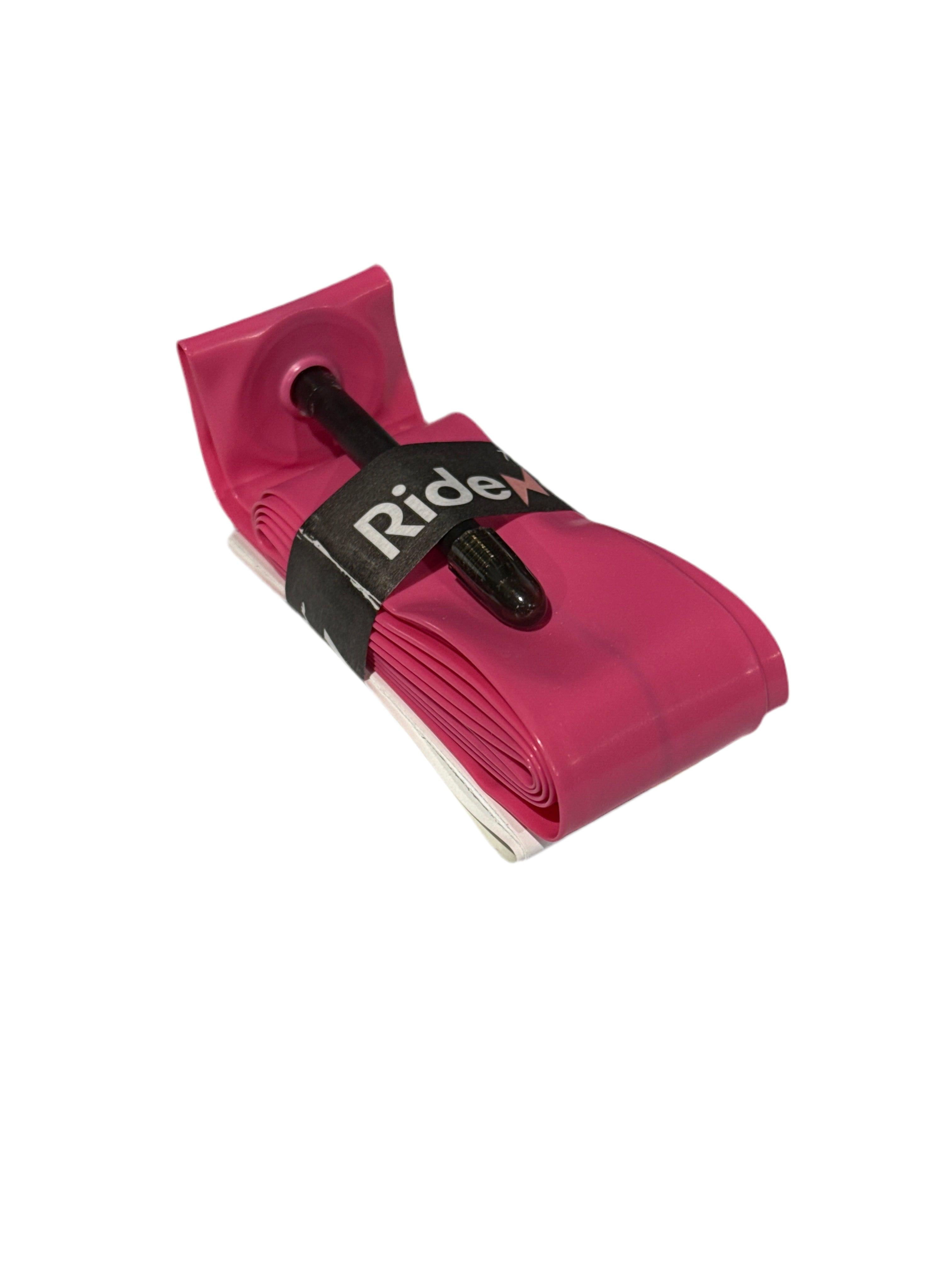 A pink RideNow 20 Inch Tube with a black Presta (French) Valve, ultra-lightweight, folded and secured by a black RideX strap, is shown on a white background.