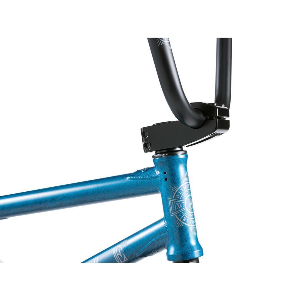Close-up of the Wethepeople Revolver 20 Inch Bike in blue, highlighting the head tube, black handlebars, stem, and aftermarket parts against a white background.