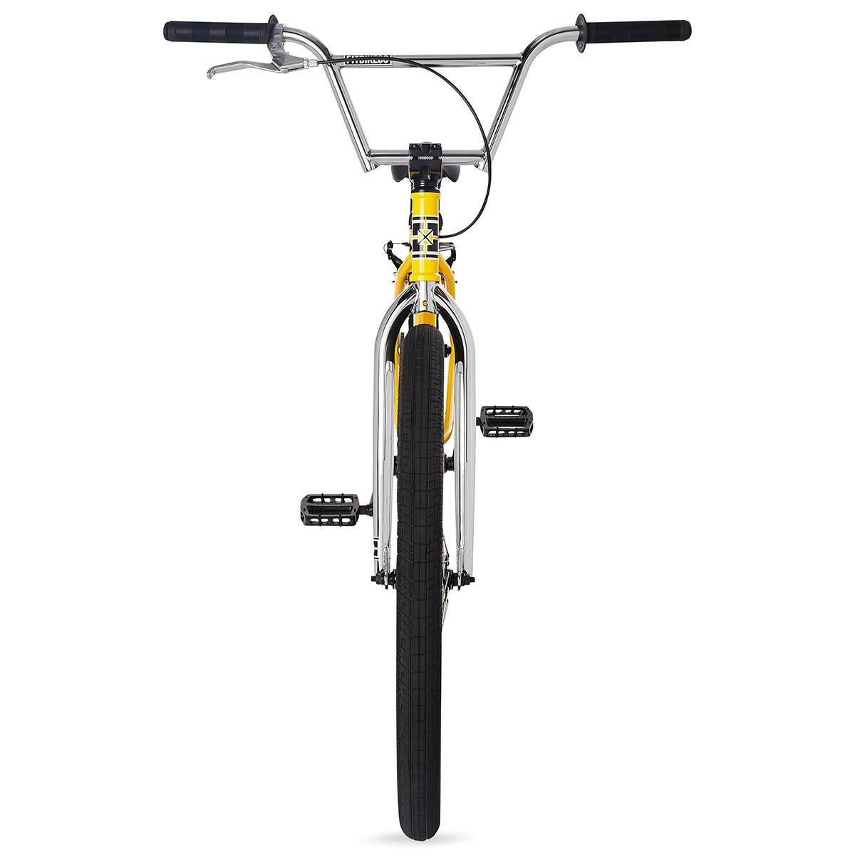 A front view of the yellow and chrome Fit CR29 Inch Bike (2023) BMX cruiser with black handlebars, black pedals, and a large 29-inch BMX front tire, set against a white background.