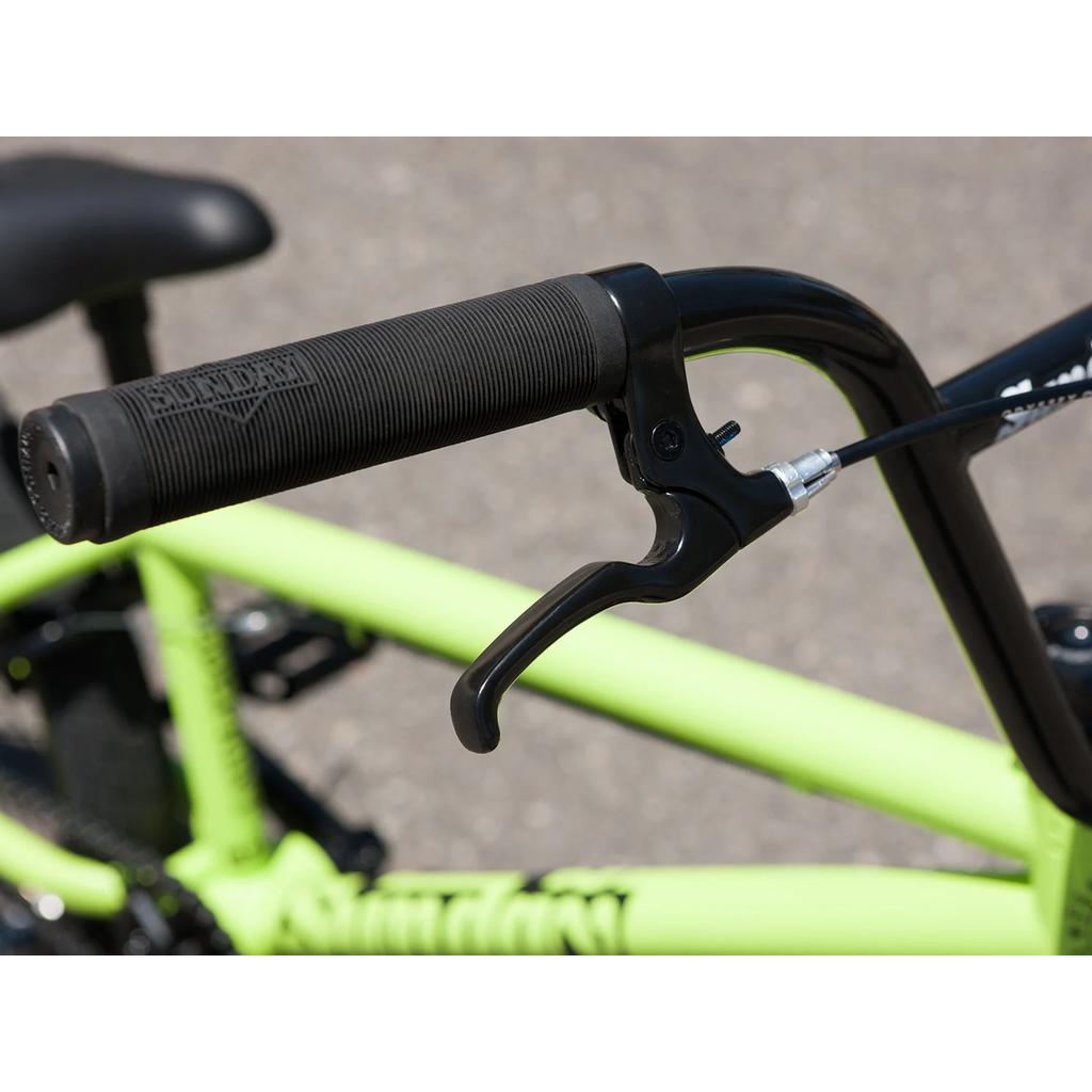 Close-up of a black handlebar with handgrip and Odyssey Springfield brakes on a light green Sunday Blueprint 20 Inch Bike (2023), photographed outdoors.
