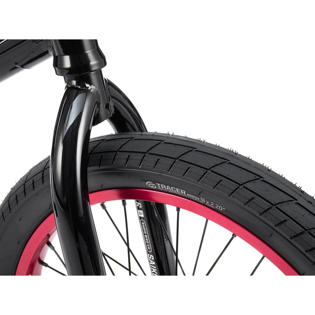 Close-up of a black bicycle front fork featuring a black tire with "Tracer 18 x 2.20" markings and a red-rimmed wheel—showcasing the Radio Saiko 18 Inch Bike with Salt Tracer Tyres.