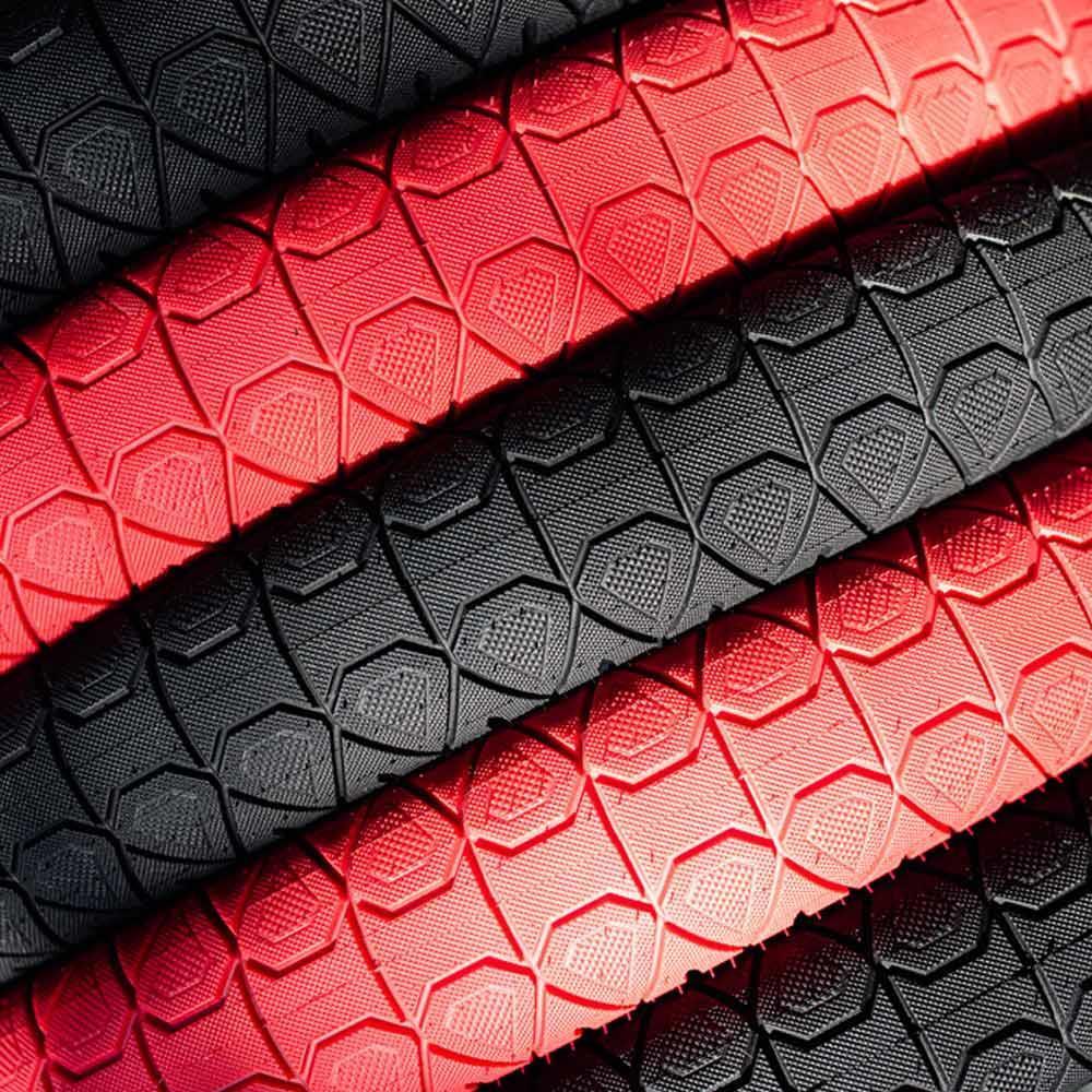 Close-up of three black and two red Subrosa Designer Tyres with a hexagonal tread, arranged diagonally in alternating colors and inspired by the Matt Ray signature tyre.