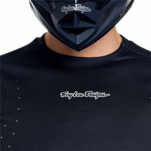 Person wearing a black TLD 26.1 Sprint Pro Jersey (Mono Black) and a dark helmet, with only the lower part of their face visible.