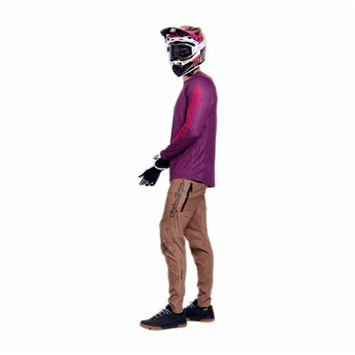 Person wearing a motocross helmet, goggles, TLD 26.1 Sprint Pro Jersey / Mono Sangria, brown cargo pants, gloves, and black sneakers stands sideways against a white background.