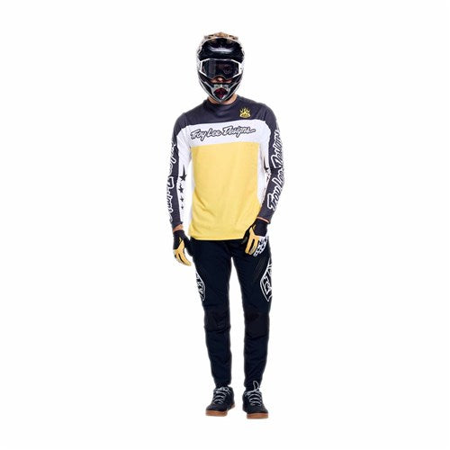 Person wearing a full motocross outfit, including helmet, TLD 26.1 Sprint Pro Jersey in Yo Moto Butter (yellow and black), black pants with white graphics, gloves, and shoes, standing against a plain white background.