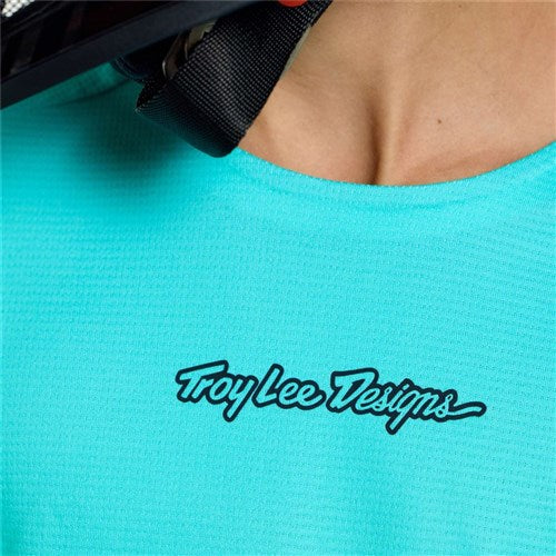 Close-up of a youth wearing the TLD 26.1 Sprint Pro Jersey (Mono Real Teal) with the "Troy Lee Designs" black script logo on the chest, made from Bluesign-approved fabrics.