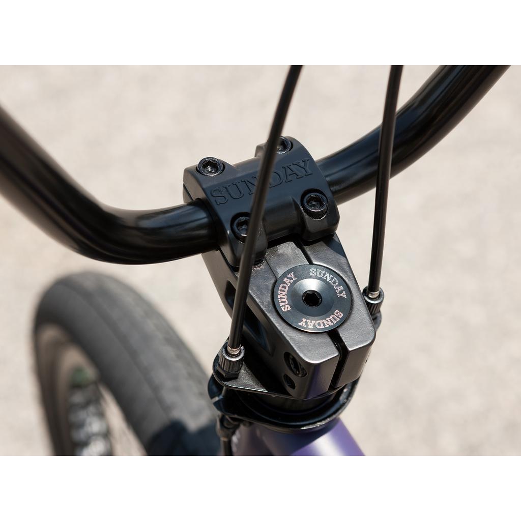 Close-up of the Sunday Forecaster Maca Grasset 20 Inch Bike's handlebar and stem, showing the "SUNDAY" branding on the stem and headset cap—a perfect detail shot for park BMX enthusiasts.