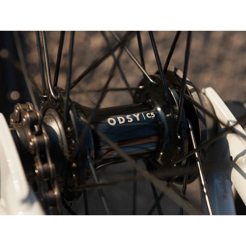 Close-up of a black bike hub with spokes radiating outward, attached to a white fork on the Sunday EX Erik Elstran 20 Inch Bike.
