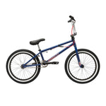 The Fit Bike Co PRK 20 Inch Bike is a blue BMX park bike with a short top tube, black saddle, handlebars, and tires, red brake cables, and standard metal pedals, shown in side profile on a white background.
