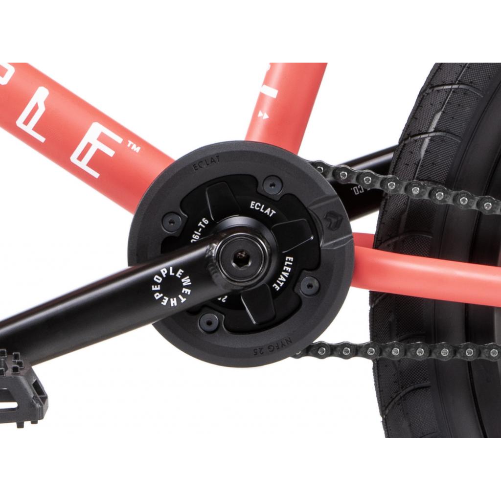 Close-up of the Eclat Elevate Guard Sprocket with a 6061-T6 alloy arm and chain on a red bike frame, shown near the rear tire.