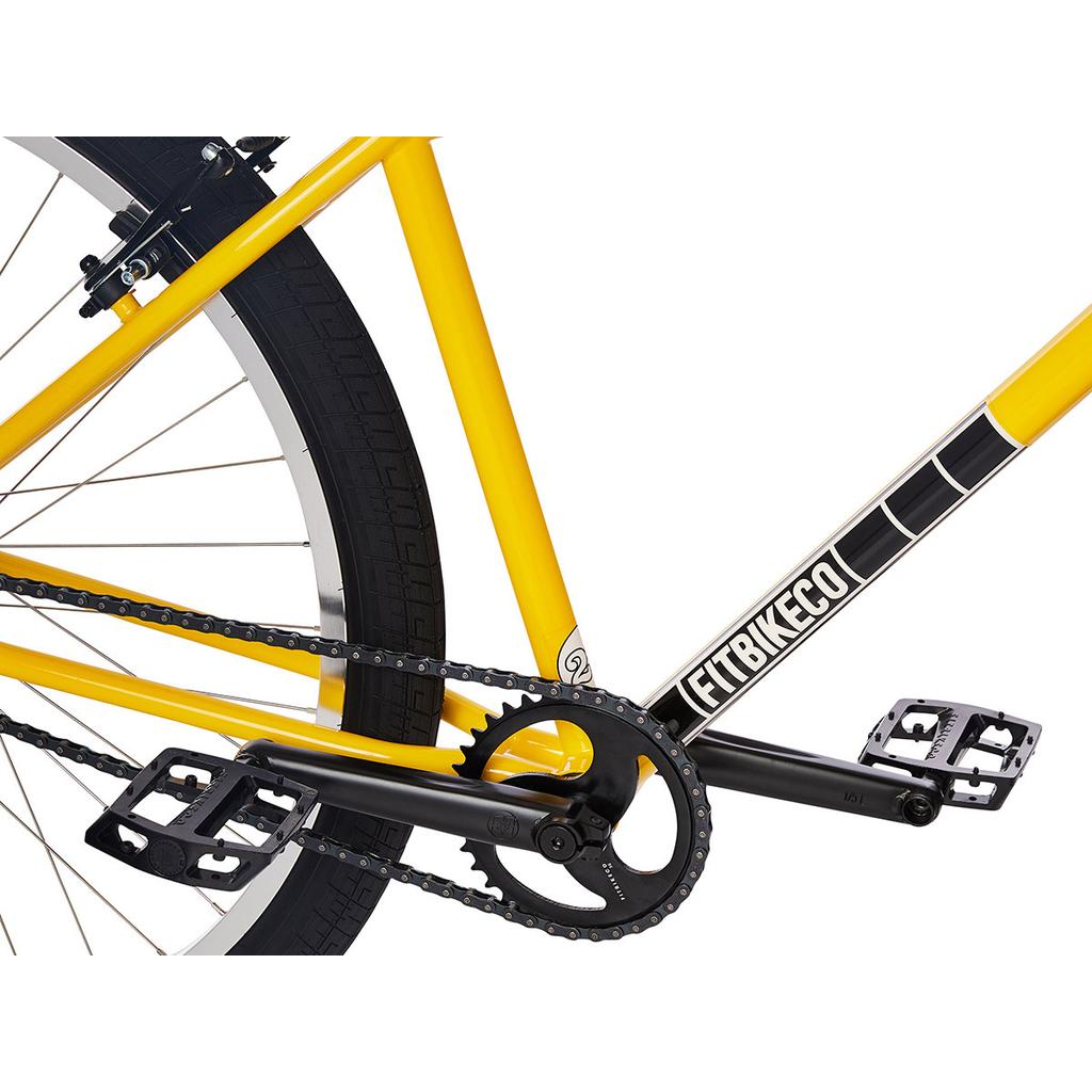 Close-up of a yellow BMX cruiser’s rear wheel, chain, black pedals, crankset, and frame labeled “LEFT8IKECO,” inspired by the 2023 Fit CR29 Inch Bike.