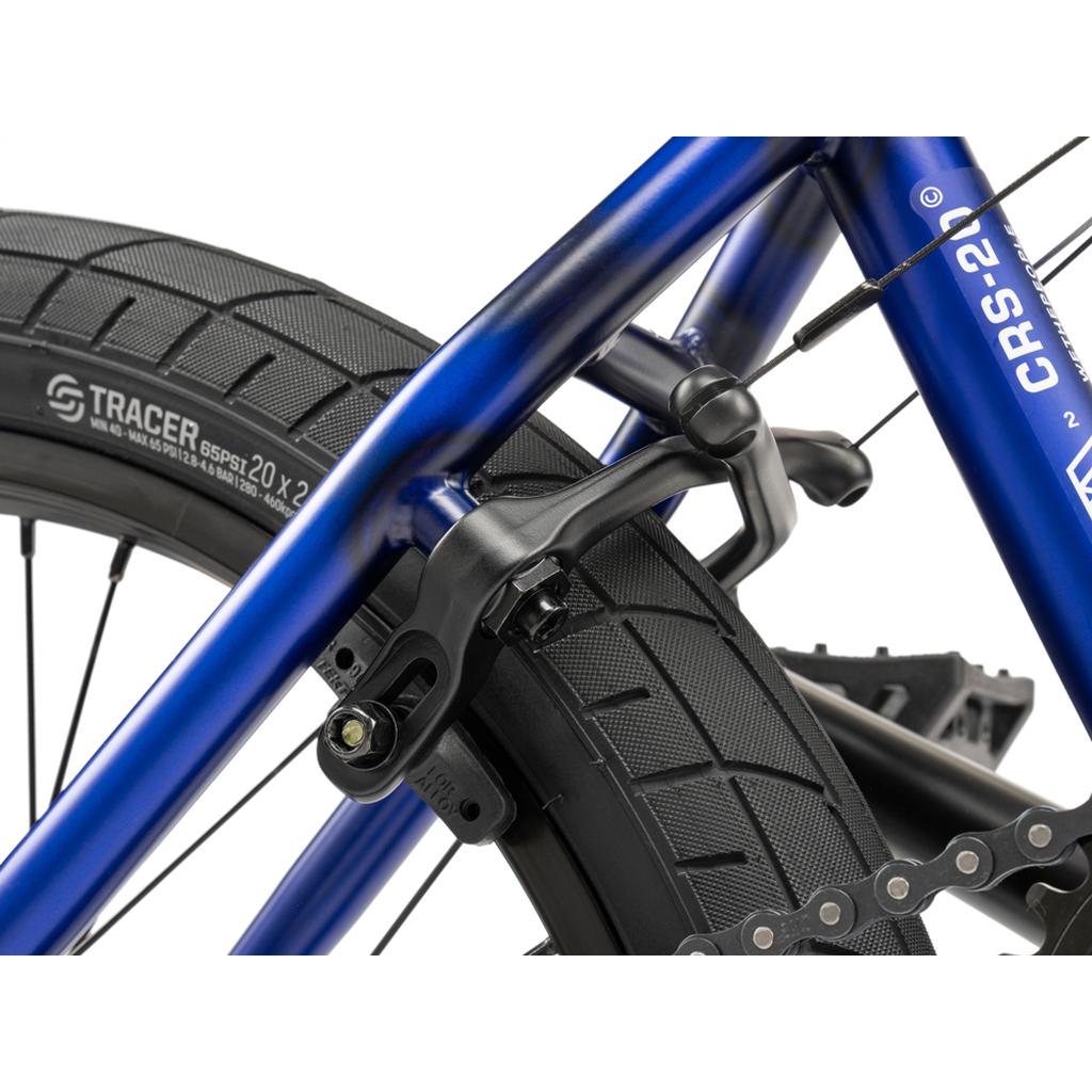 Close-up of the Wethepeople CRS FC 20 Inch Bike’s rear wheel with a black V-brake on its blue frame and a thick, knobby tire—perfect for entry-level BMX riders.