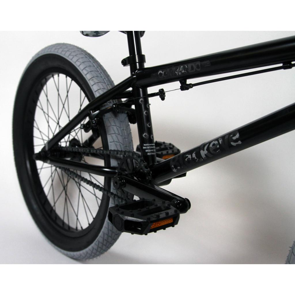 Close-up of the rear half of the Black Eye Commando 20 Inch Bike (2022), an entry-level BMX with gray tires, shown against a white background.