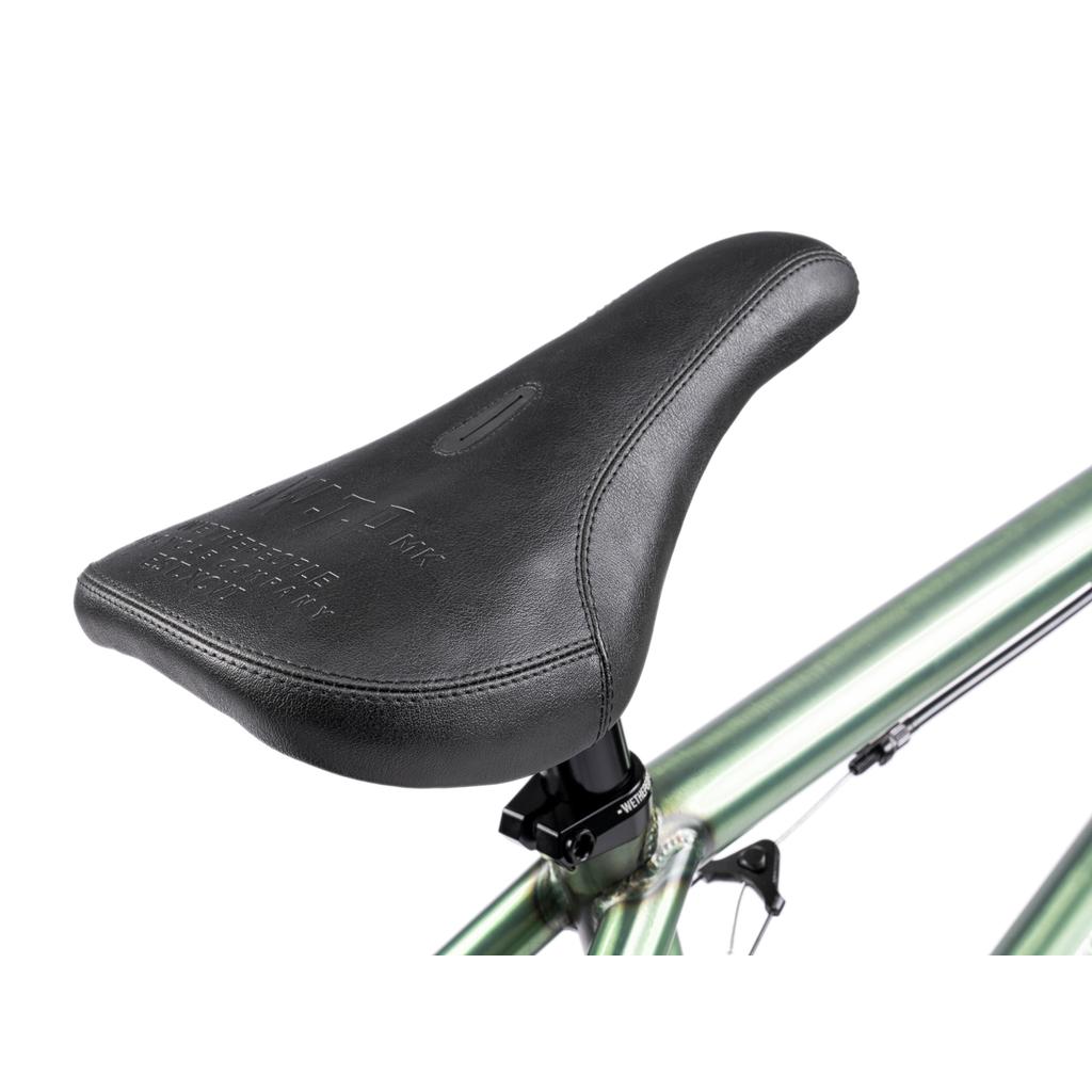 Close-up of a black bicycle seat mounted on the metallic green frame of a Wethepeople Revolver 20 Inch Bike, highlighting the seat post and top tube—perfect for BMX enthusiasts interested in aftermarket bike parts.