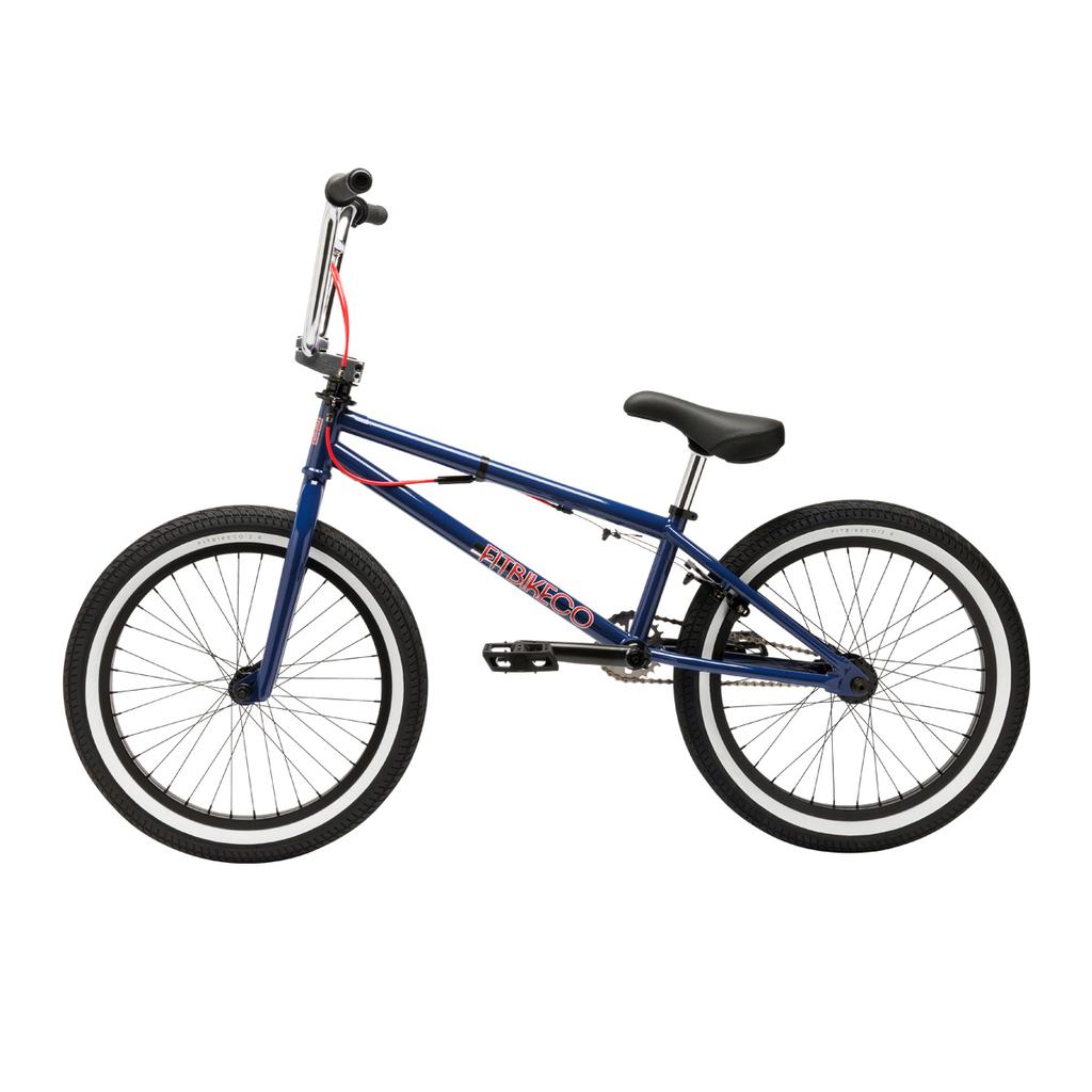The Fit Bike Co PRK 20 Inch Bike is a blue BMX park bike featuring a short top tube, black seat and handlebars, red brake cable, and black tires with white rims, shown in profile on a white background.
