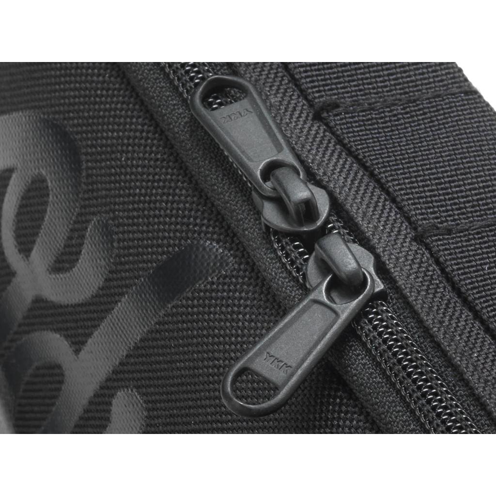 Close-up of two black zipper pulls on the textured black fabric ODYSSEY Switch Pack V2 Hip Bag, ideal for use as a bike bag or hip bag.