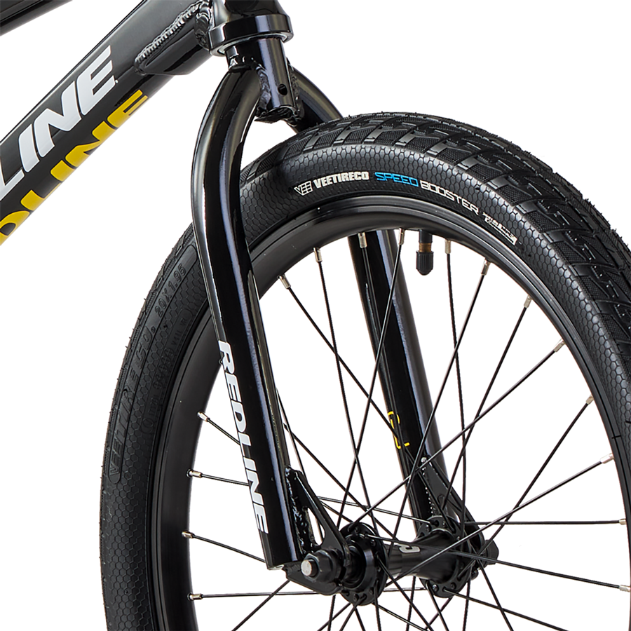Close-up view of a black bicycle tire labeled "vee tire co speed booster" mounted on a wheel with reflective sidewall, attached to a Redline Proline Expert XL Bike frame.