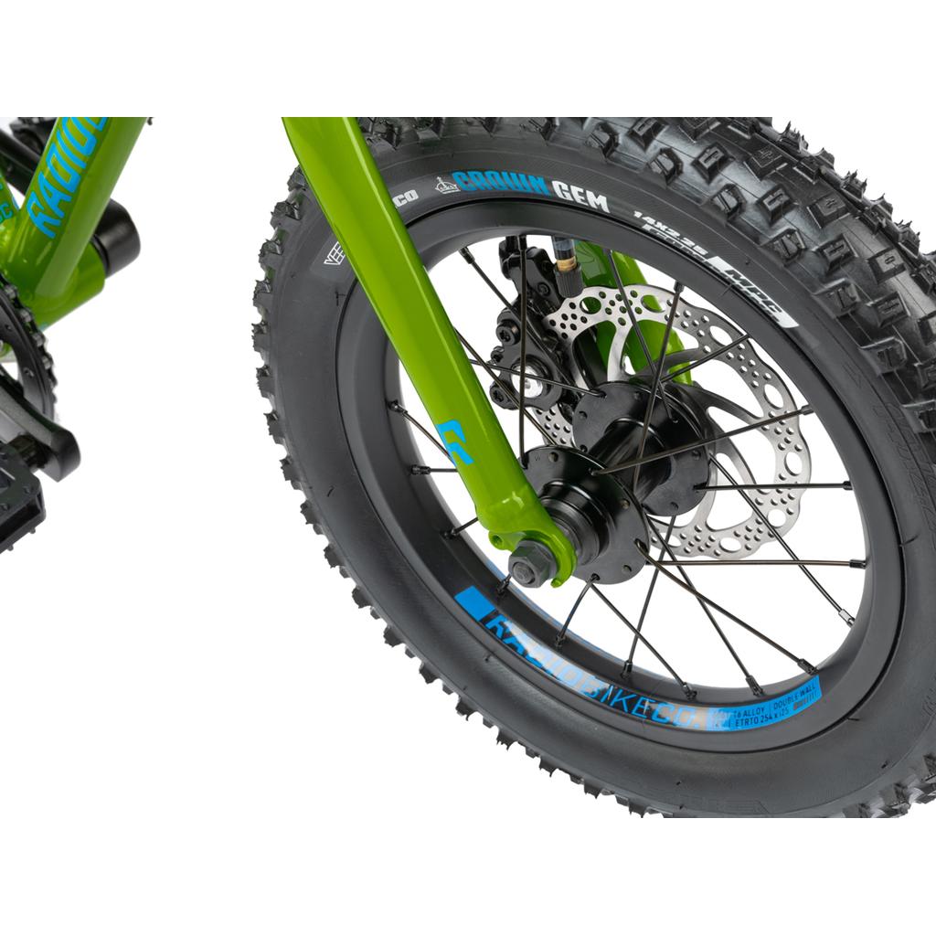 Close-up of the Radio Zuma 14 Inch Bike’s front wheel, showing its thick tread tire, disc brake, spokes, and fork—showcasing quality details on this kids mountain bike. Brand markings appear on both the rim and fork.