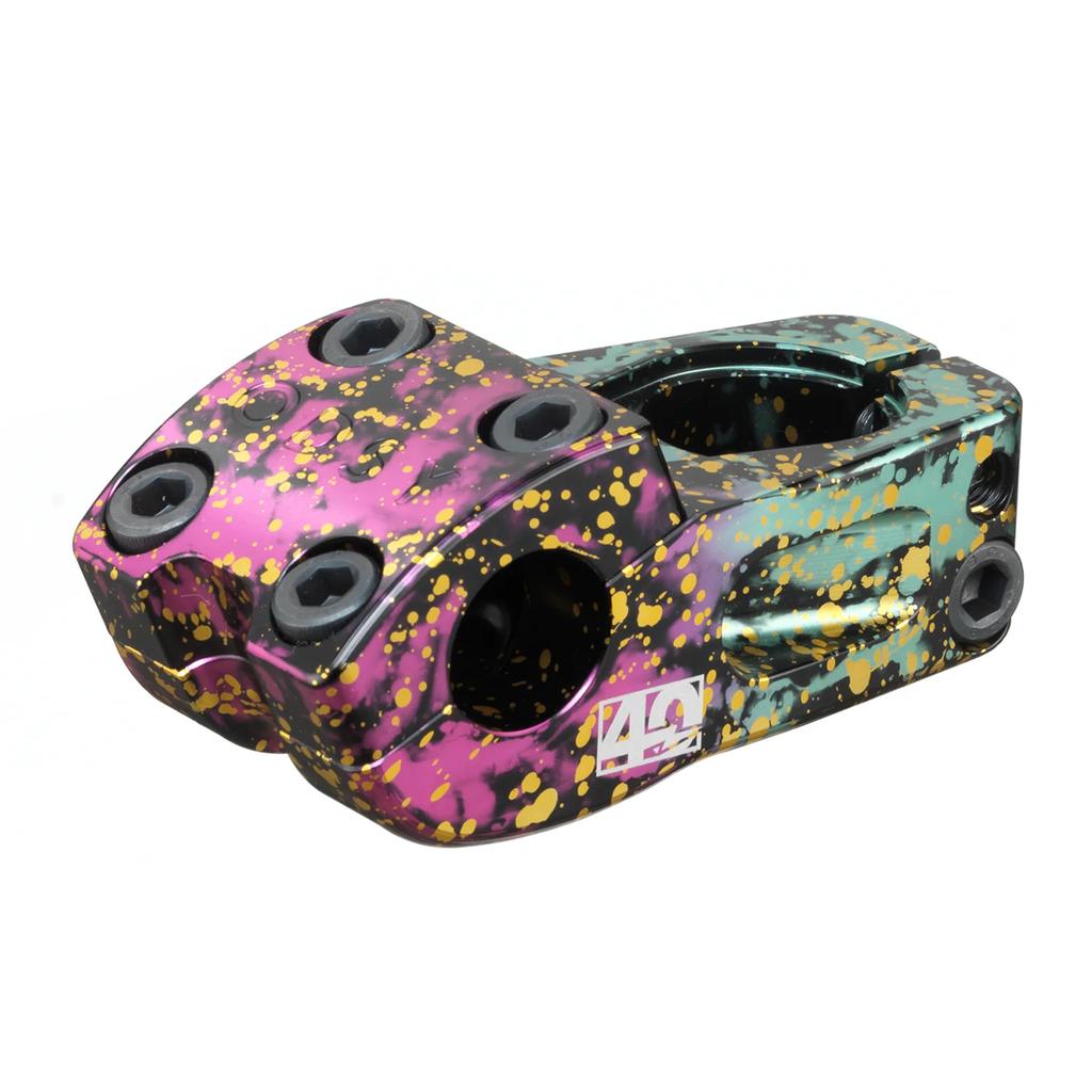 The Odyssey Walsh Stem (40th Anniversary) features a black base with pink, teal, and yellow splatter paint, multiple bolt holes, and is the Corey Walsh Signature design celebrating Odyssey’s 40-year anniversary.