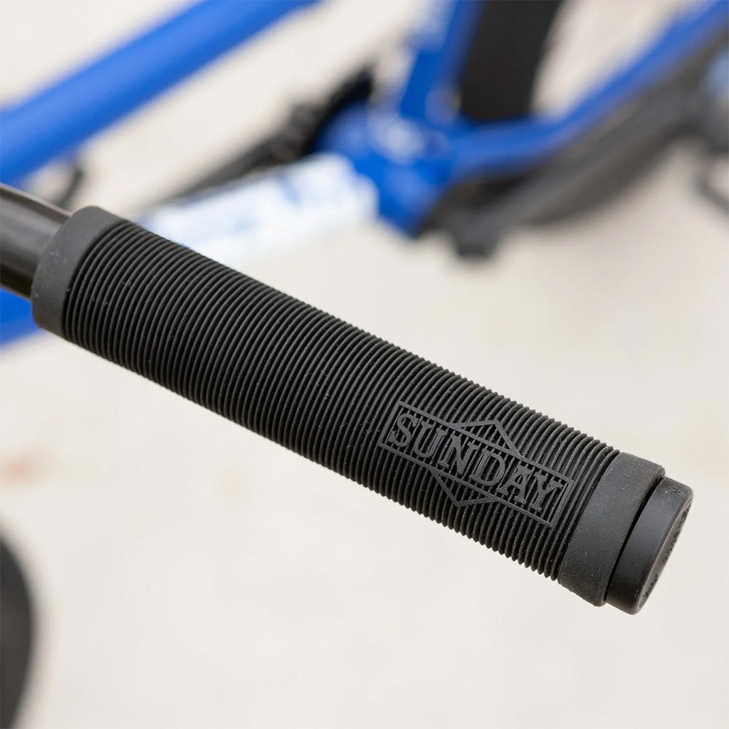 A close up of the handle of a blue Sunday Blueprint 20 inch bike.