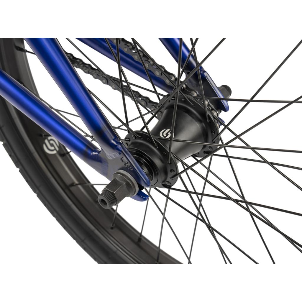 Close-up of the Wethepeople CRS FC 20 Inch Bike’s rear wheel, highlighting the freecoaster hub, spokes, axle, and part of its blue frame.