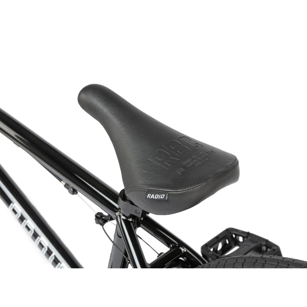 Close-up of a black BMX seat featuring "RBC" and "RADIO" logos, mounted on the Radio Revo Pro 20 Inch Bike, shown against a white background.
