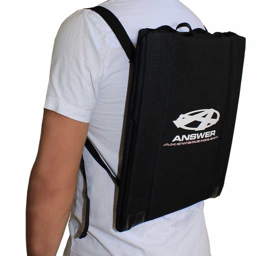 Person using the Answer Stadium Seat, a black protective seat with adjustable straps and label, worn over a white T-shirt—perfect for comfort and support during BMX racing.