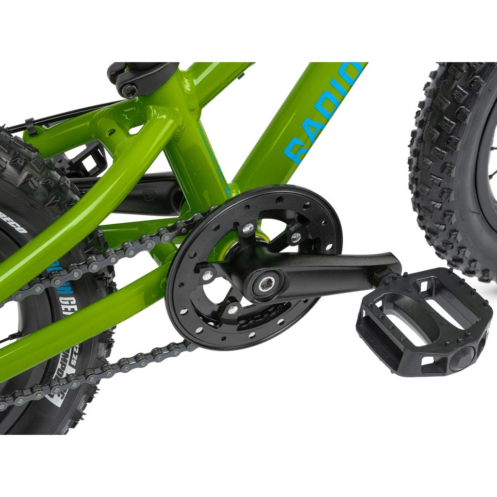 Close-up of the pedal, crank, and chainring on the green Radio Zuma 14 Inch Bike, highlighting the chain, frame detail, and fat tires of this lightweight kids’ mountain bike.