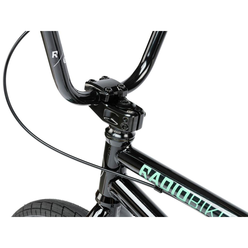 Close-up of the black handlebar, stem, and front brake cable on the Radio Saiko 18 Inch Bike, with "RADIOBIKES" branding on the frame and Salt Tracer Tyres visible.