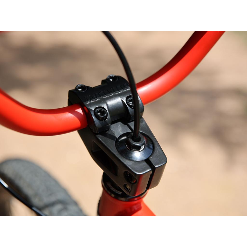 Close-up of a red handlebar and black stem with a brake cable on the Fairdale Taj 27.5 Inch Bike (2023), taken outdoors—showing perfect details for BMX commuters and single speed enthusiasts.