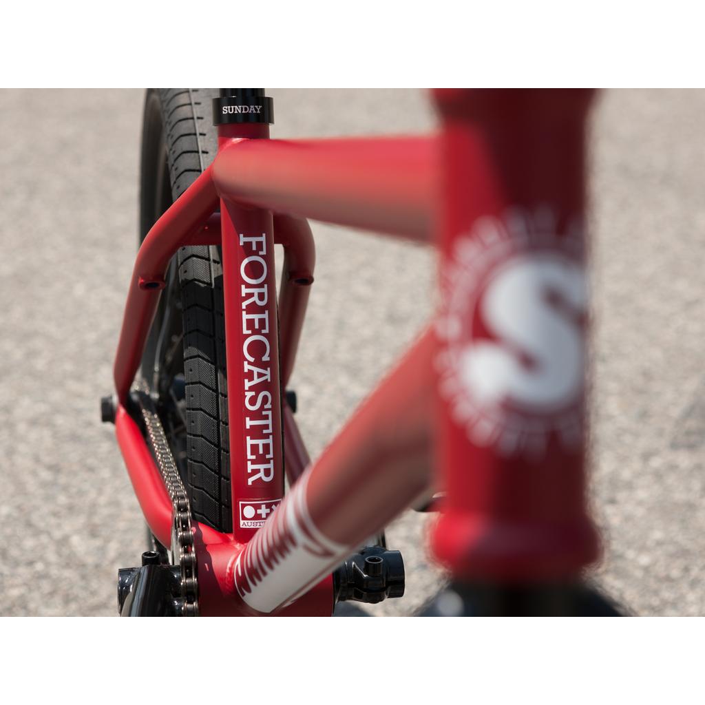 Close-up of the Sunday Forecaster 20 Inch Bike's red chromoly frame with "FORECASTER" on the seat tube, showcasing detailed rear wheel and frame features of this BMX bike.