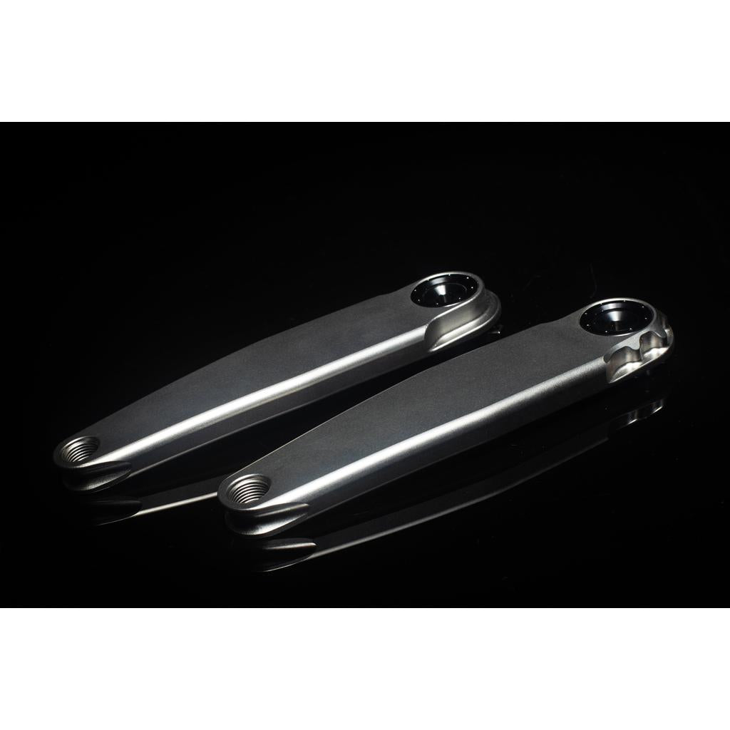 The 5DEV Titanium RGXC Cranks, featuring a lightweight metallic design, are displayed side by side on a black reflective surface.