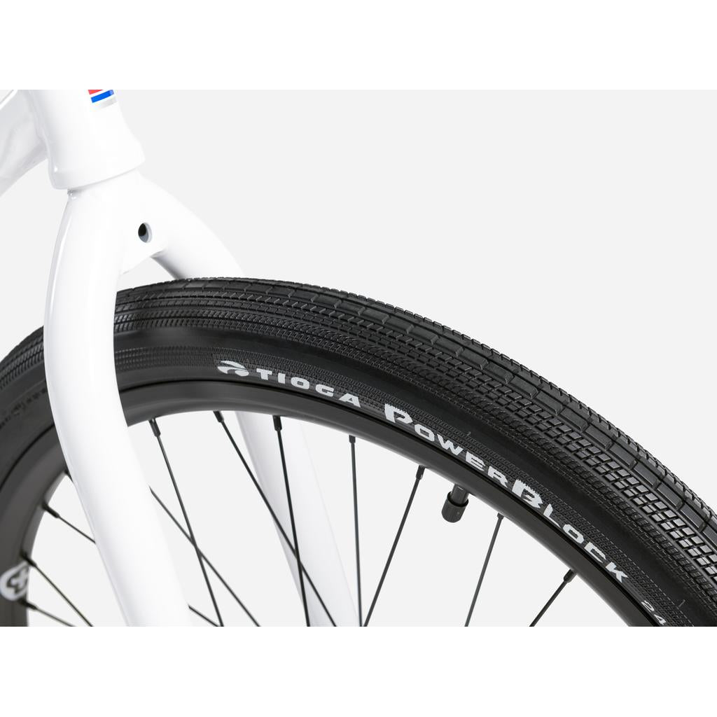 Close-up of a black tire on the front wheel of a Wethepeople Atlas 24 Inch Bike, showing the spokes and fork against a plain background.