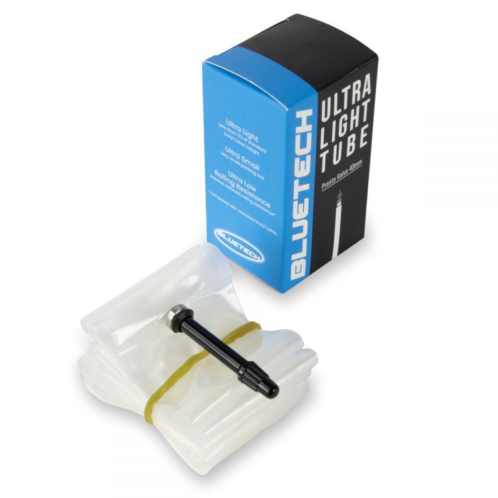 An Excess Ultralight Tube (OS20) for bicycles is displayed beside its blue and black packaging, featuring an alloy valve. The thermoplastic polyurethane tube is folded and held together with a rubber band.
