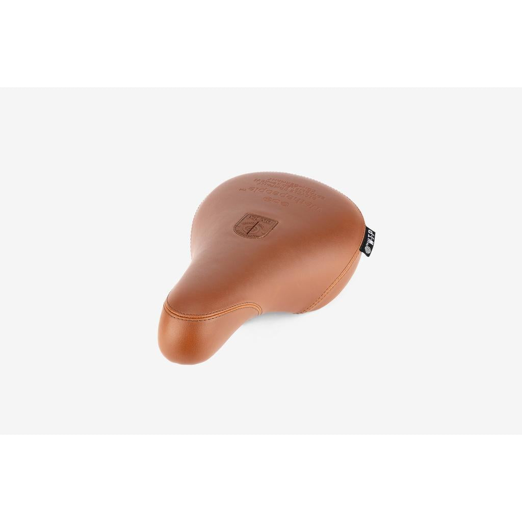 The Wethepeople Team Pivotal Fat Seat is a brown leather BMX seat featuring embossed branding and a stitched logo, shown against a plain white background.