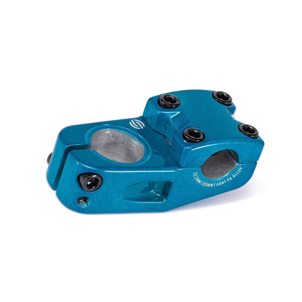 The Salt Am V2 Top Load Stem (22.2mm Clamp) is a blue anodized BMX bike stem crafted from durable 6061 T6 alloy, featuring four black bolts on top, two on the side, and shark tooth clamping for enhanced grip. This stem displays precise machining details and proudly showcases the Salt logo.