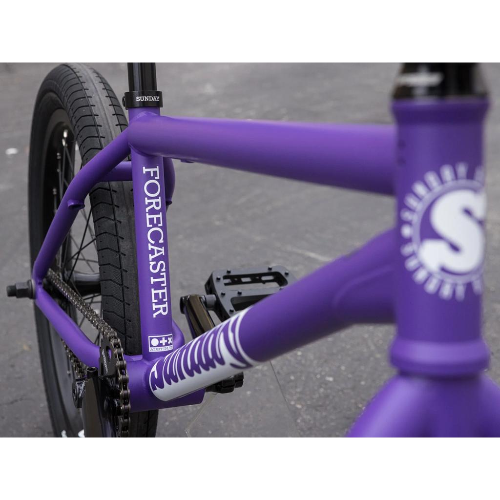 Close-up of the Sunday Forecaster 20 Inch Bike’s chromoly BMX frame with "Forecaster" printed on it, Odyssey parts, visible rear wheel, pedals, and part of the handlebars.