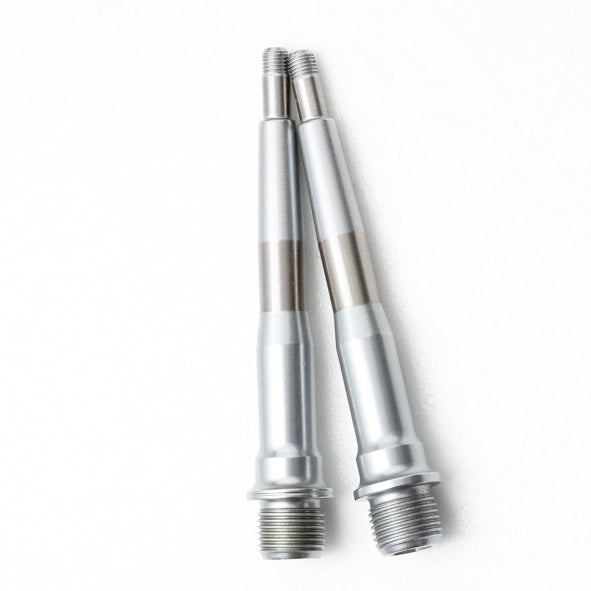 A pair of HT Components X3 Spindles, metallic and cylindrical with threaded ends—perfect replacements for HT X3 pedals—are displayed side by side on a white surface.