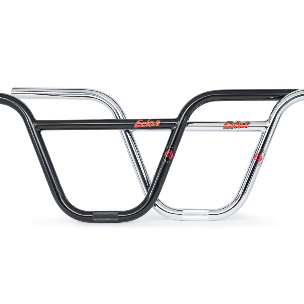 Two bicycle handlebars, one black and one chrome, are positioned side by side. Both BMX handlebars feature red and yellow “Eclat” logos and a small circular emblem on the side, identifying them as Eclat Chocolate Bars (22.2mm Clamp).