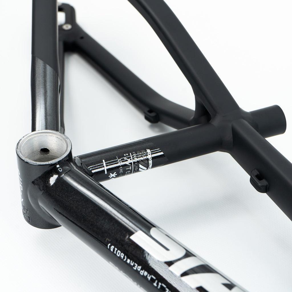 Close-up of a Staystrong V5 Disc Mini Frame in black aluminium on a white surface, showcasing its 6061 alloy tubing, bottom bracket features, and crisp white decals.